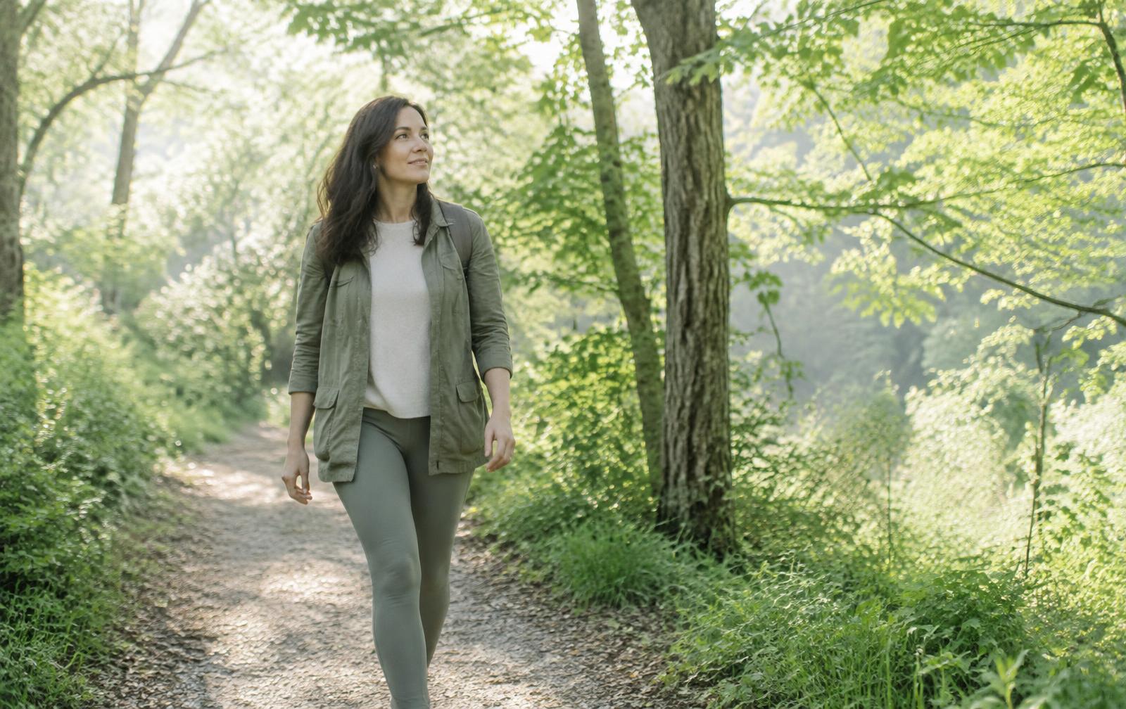 Woman walking on a sunlit forest trail